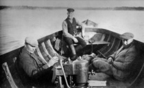 Texten för bilden: Jaktfärd, fr.v. Frans Jonasson, Valter Jonasson och V. Byman å Pörtö 1921.
Motorn är Borgå Båtvarv's modell Borgå 2. Jonassonin perhealbumi.